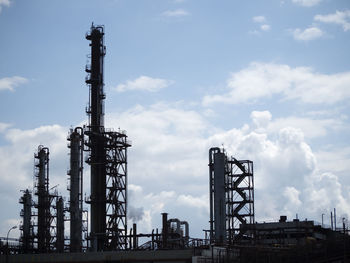 Low angle view of oil refinery  against sky