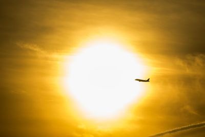 Low angle view of silhouette airplane flying against sky during sunset