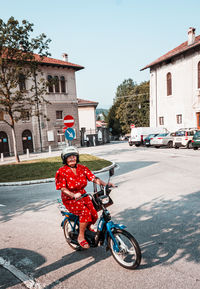 Portrait of boy riding motorcycle on road by buildings in city