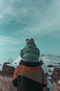 Rear view of man standing on snow against sky