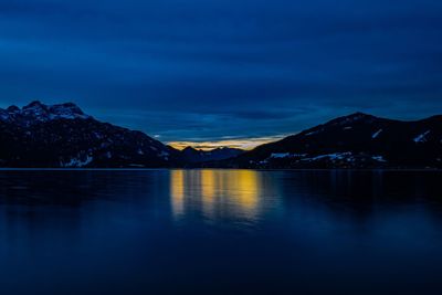 Scenic view of lake and mountains against sky at dusk