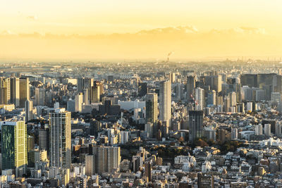 Aerial view of modern buildings against sky in city during sunset