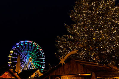 Low angle view of illuminated ferris wheel against sky at night