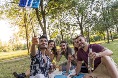 Cheerful friends having drink while doing selfie