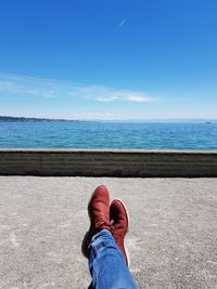 Low section of man on sea shore against sky