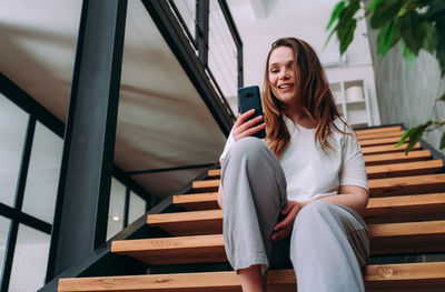 Full length of young woman sitting on staircase