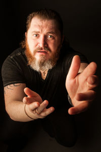 Portrait of man standing against black background