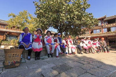 People standing by tree against sky