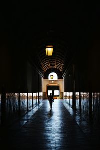 Rear view of silhouette man walking in illuminated tunnel