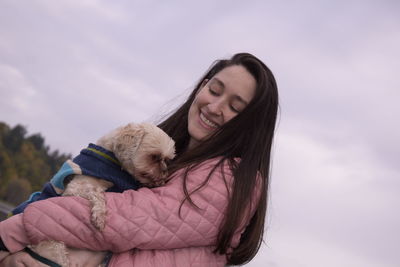Portrait of smiling woman with dog against sky