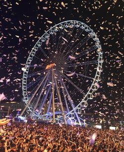 Illuminated ferris wheel against sky at night