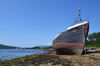 Boat moored on beach against clear sky