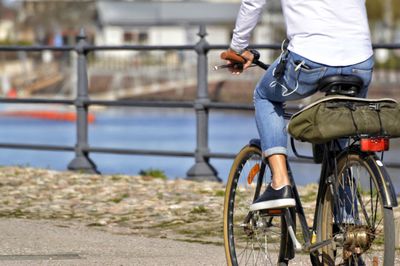 Low section of man riding bicycle on road in city