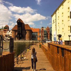 Rear view of woman standing on boardwalk against national maritime museum