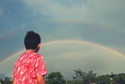 Side view of man looking at rainbow in sky