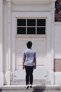 Rear view of man levitating by closed doors in house