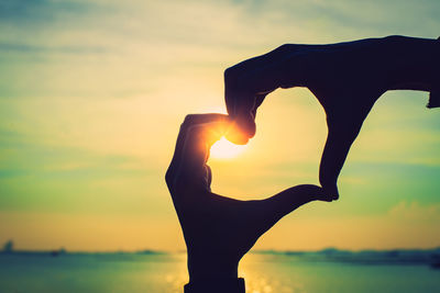 Silhouette hand against sky during sunset
