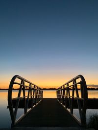 Pier over sea against clear sky during sunset