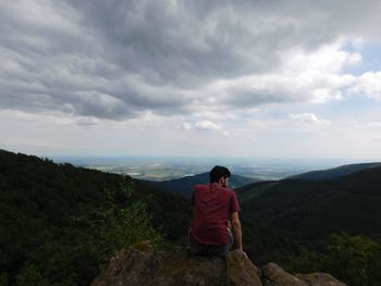 Rear view of man sitting on cliff