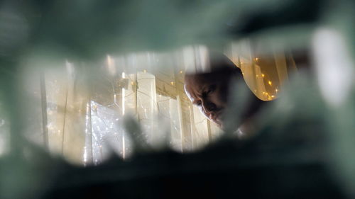 Portrait of young woman looking through glass window