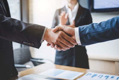 Cropped image of business people shaking hands over table