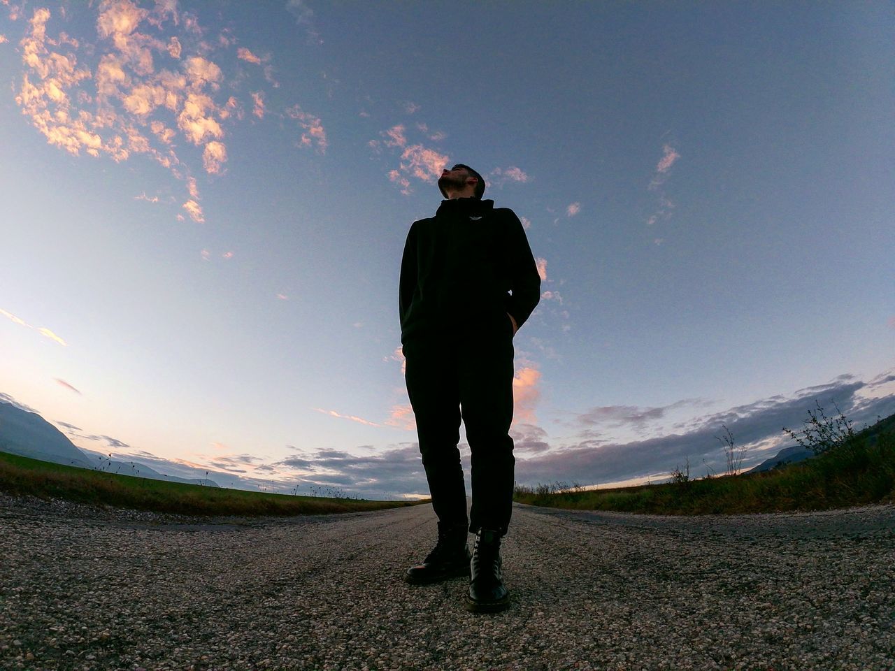 REAR VIEW OF MAN STANDING ON FIELD