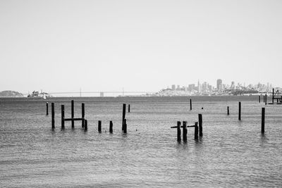 Wooden posts in sea against clear sky