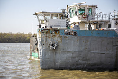 Nose of wrecked boat in a winter day at river coastline. side view.