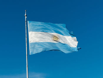 Low angle view of flag against blue sky