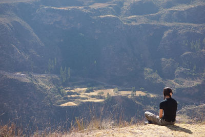 Rear view of woman sitting against mountains