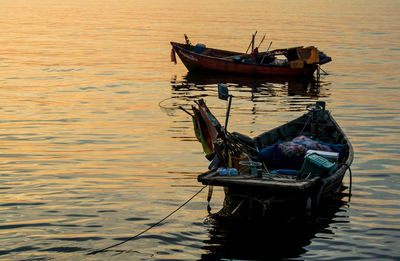 Boats moored on sea at sunset