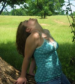 Young woman looking away while relaxing on field