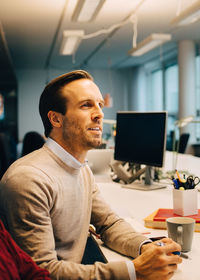 Confident businessman sitting at illuminated desk in creative office