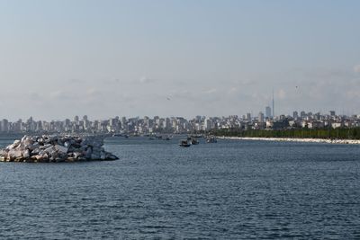 Scenic view of sea by buildings against sky