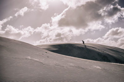 Silhouette man on sand dune at desert