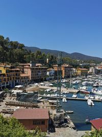 Sailboats in city by sea against clear blue sky