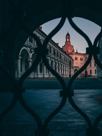 Historic building seen through fence in city during sunset