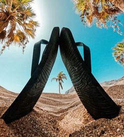 Surface level of flip-flops on sand at beach against sky