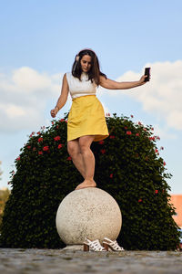 Woman standing by tree against sky