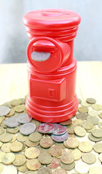 Close-up of red piggy bank by coins on table