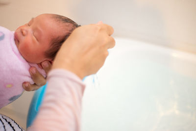 Cropped image of mother giving bath to newborn baby