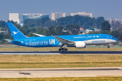 Airplane flying over airport runway against blue sky