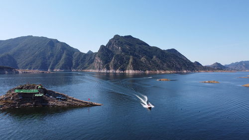 Scenic view of lake and mountains against clear blue sky