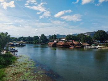 Scenic view of river by buildings against sky