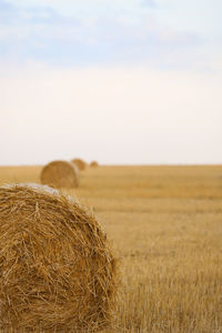 Hay bales on field against sky