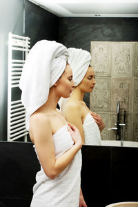 Midsection of woman with arms raised in bathroom