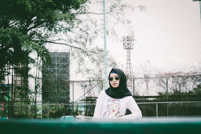 Portrait of young woman standing against trees