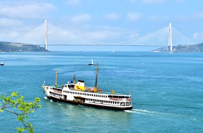 Bridge and ferry over the sea against the sky