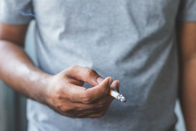 Midsection of man holding cigarette