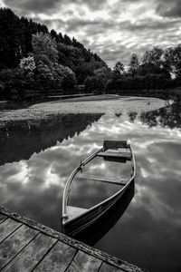 Boat moored on lake against sky